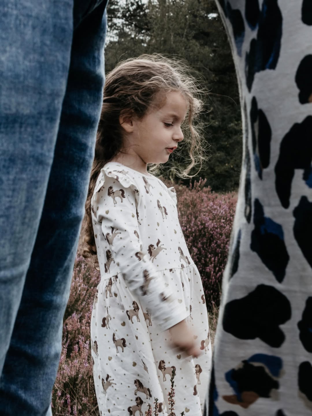 Meisje in witte jurk tussen haar ouders op de heide