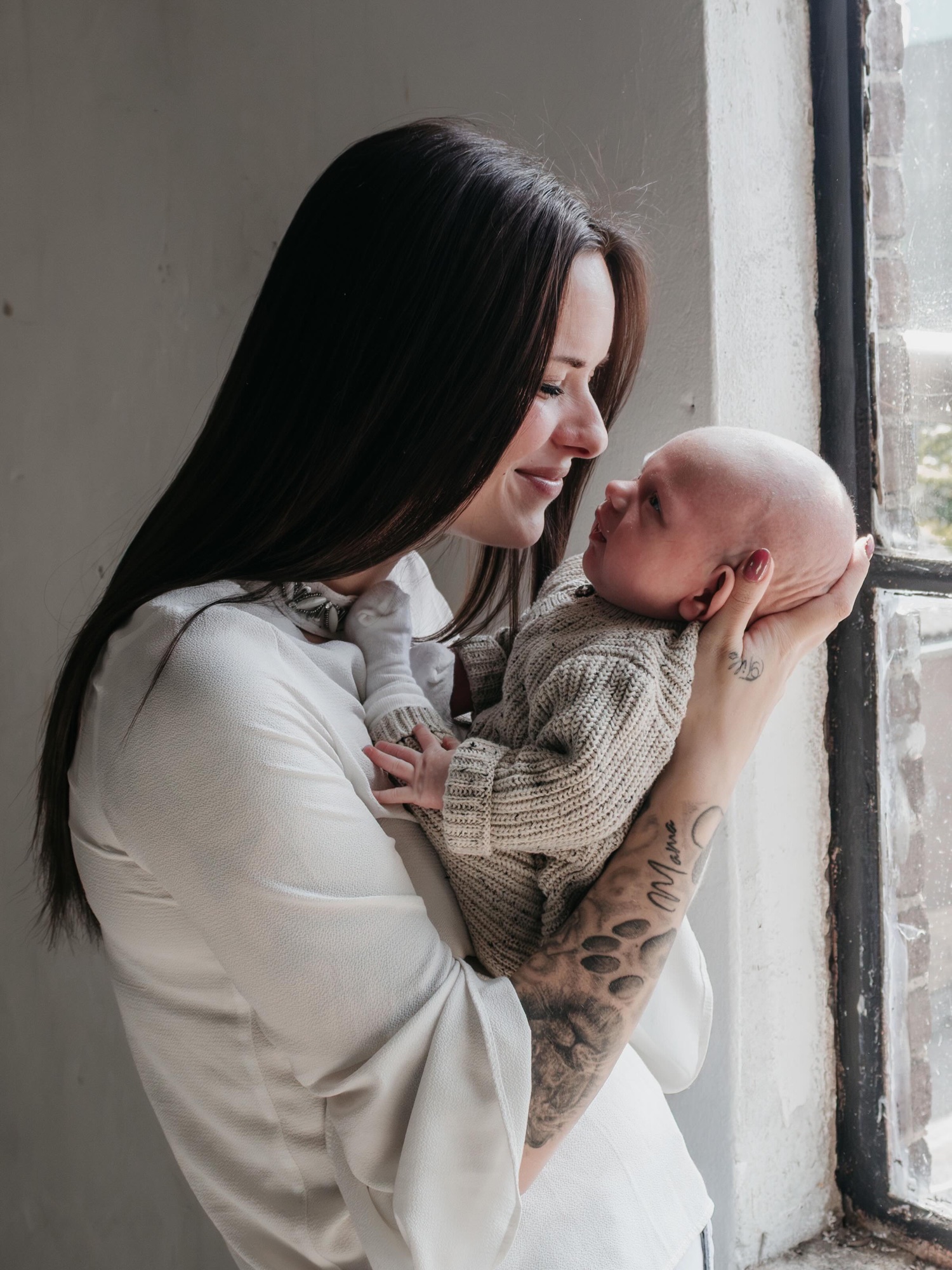 Moeder kijkt naar haar pasgeboren baby bij het raam