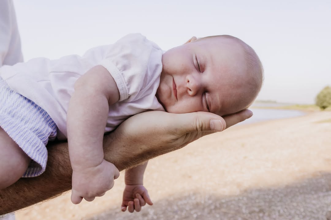 Pasgeboren baby slaapt op de arm van papa buiten