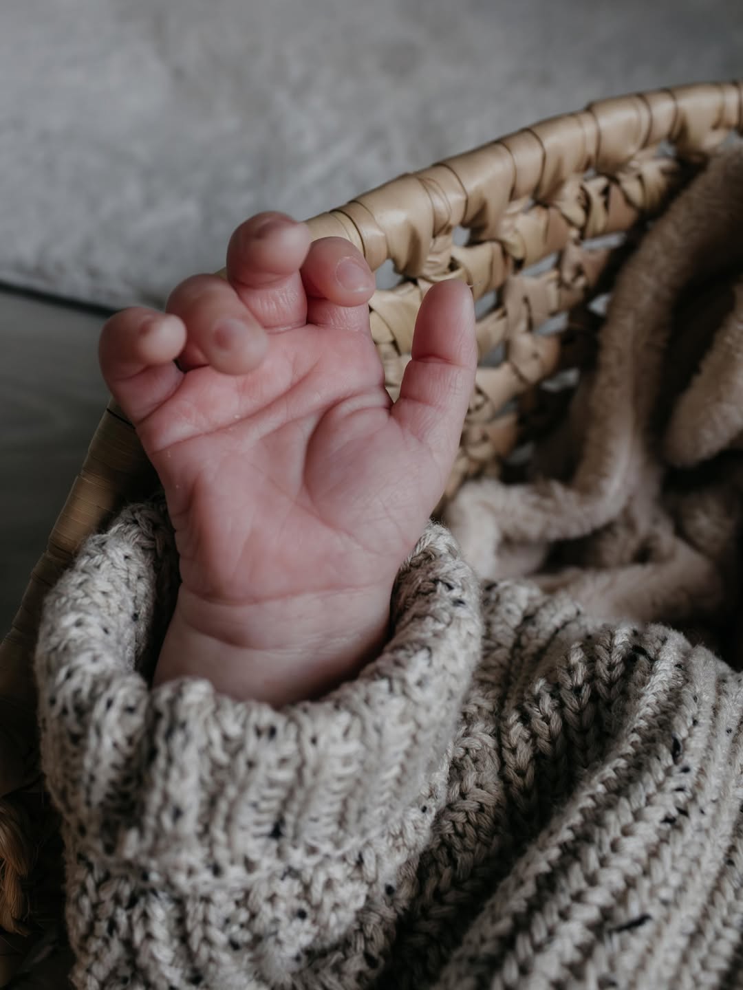 Handje van een pasgeboren baby in een gebreid pakje