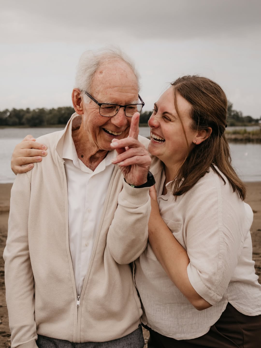 Opa en kleindochter lachen samen op het strand